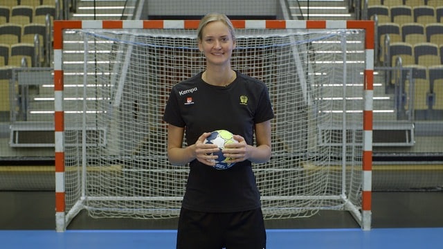 handball women standing infront of a goal holding a ball