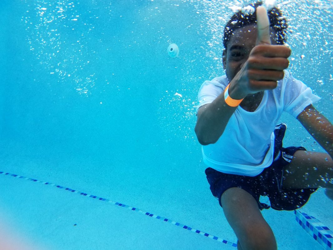 kid under water giving the thumbs up