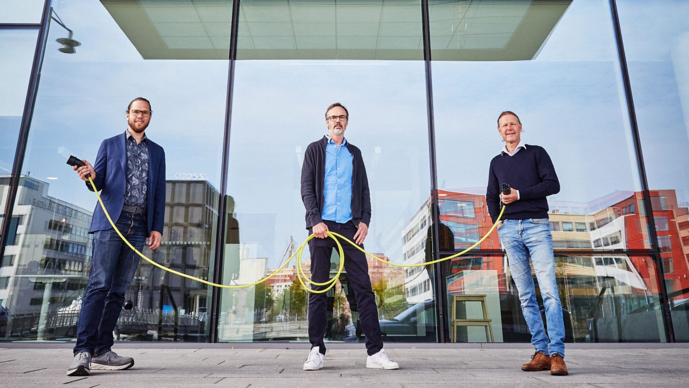 three men holing a charging cable