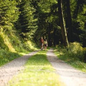 two girls walking down a road in the woods